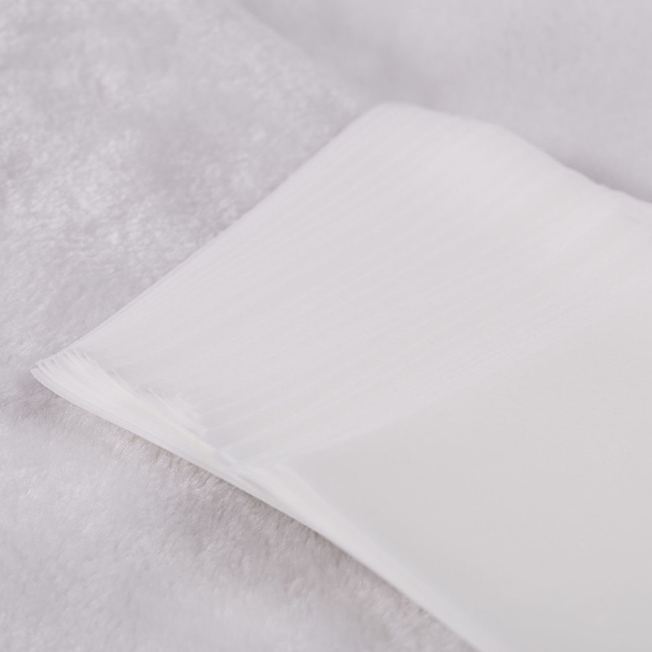 Close up of a bunch of dryer sheets, sitting on a white cloth  .