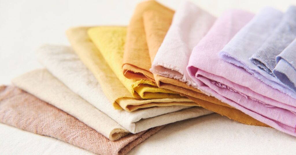 A stack of colorful fabric swatches, including delicate fabrics like silk, lace, and fine wool, emphasizing proper care and washing techniques.