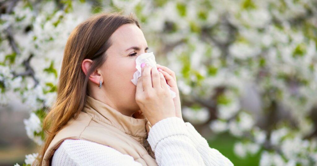 A person with a tissue, likely due to common allergies from pollen. It's important to keep laundry clean during allergy season.