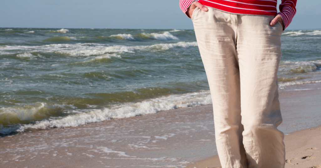 Person walking on the beach in summer clothes & linen pants.