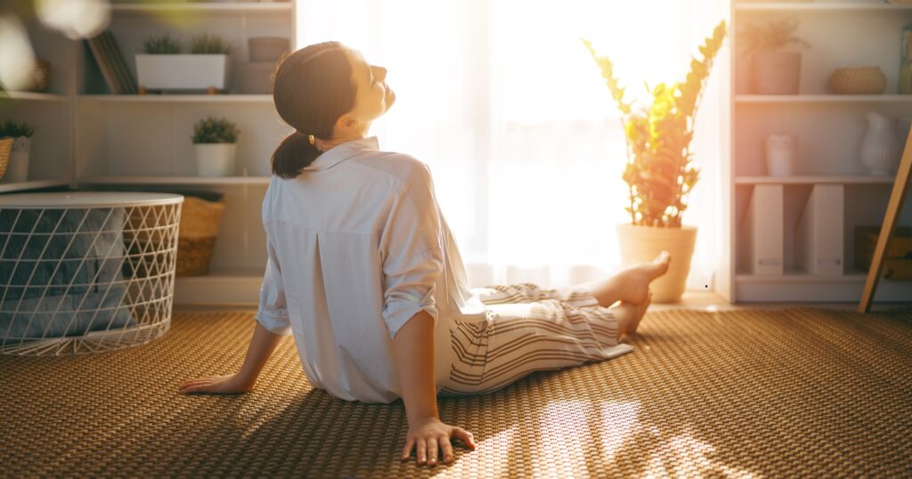 A woman relaxing in a clean, organized room after finishing laundry, representing why clean clothes matter for a calm mind, self-care, and productivity