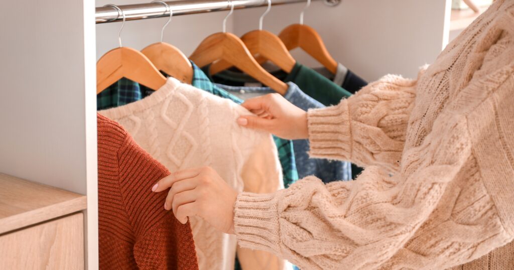 Winter sweaters and heavy jackets hanging neatly in a closet, showing thick fabrics like wool, fleece, and outerwear ready for proper cleaning and care.