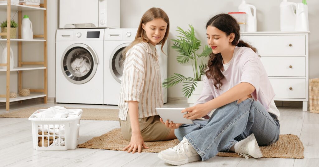 Student folding clothes in a dorm room showing dorm laundry tips for back-to-campus living